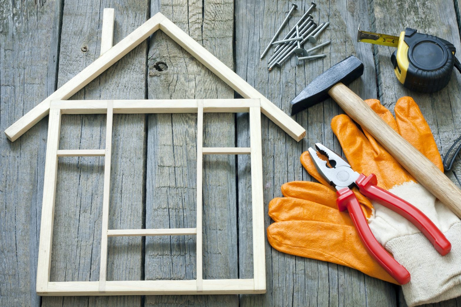 Maison en bois miniature posée sur un plancher avec des outils à côté